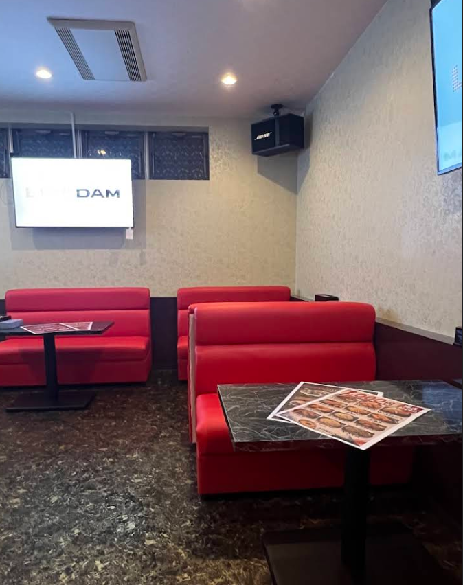 赤いソファ、テーブル、カラオケがあるTell meの店内